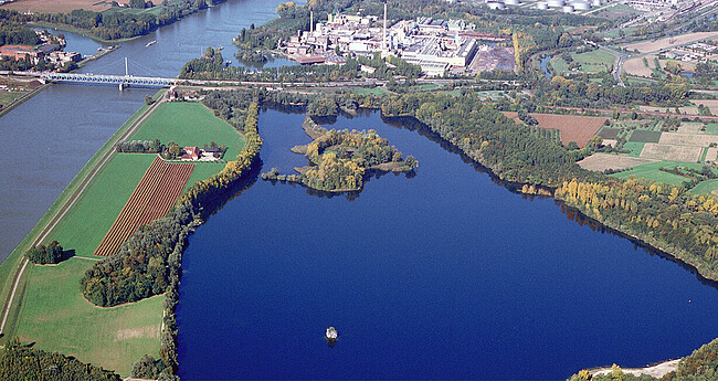 Luftaufnahme vom Knielinger See und Federbach am Rhein mit angrenzenden Äckern, Wiesen und Wäldern sowie Industrieanlagen und Versorgungseinrichtungen