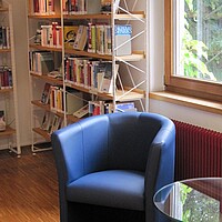 Leseplatz mit blauem Sessel und Glastisch in der Stadtbücherei Albstadt - Zweigstelle Tailfingen