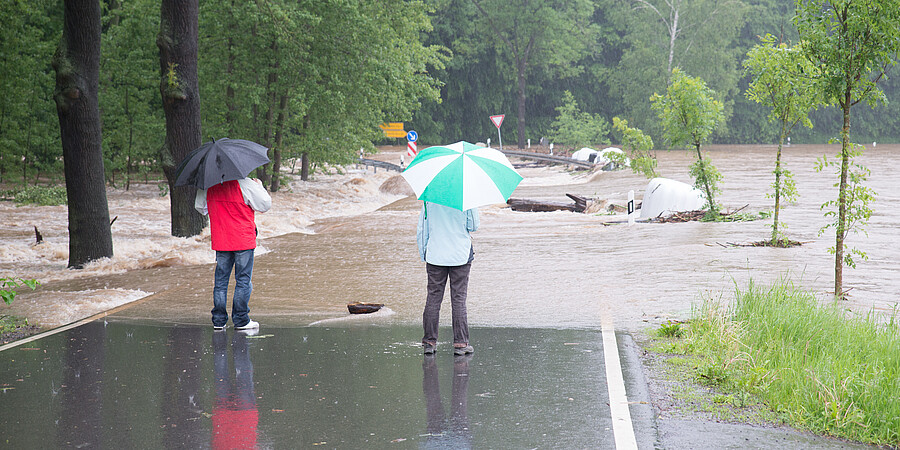 Passanten betrachten die überflutete Straße