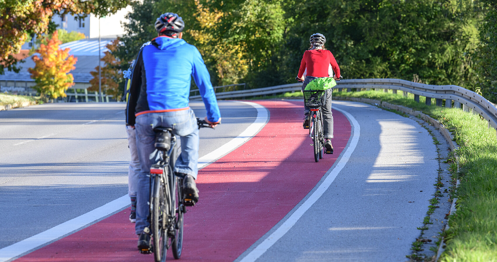 Zwei Fahrradfahrer fahren auf einem rot gekennzeichneten Radweg. man sieht sie von hinten
