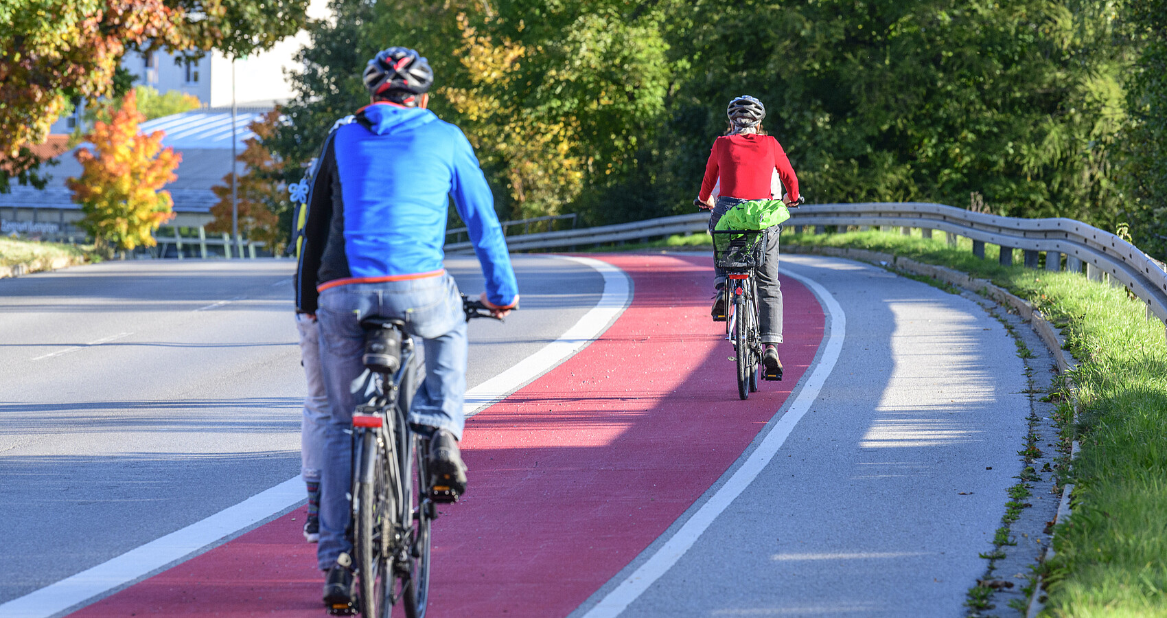 Zwei Fahrradfahrer fahren auf einem rot gekennzeichneten Radweg. man sieht sie von hinten