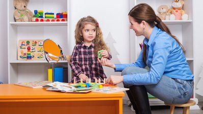 Eine Ergotherapeutin mit einem kleinem Mädchen bei einem Steckspiel