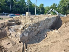 Freigelegte Bunkerruine. Man sieht dicke Betonwände und Stahl-Armierungen. Die Erde um den Bunker herum wurde teilweise abgetragen.