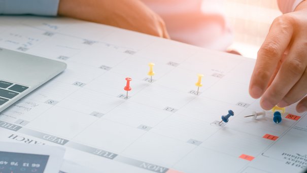 Das Bild zeigt eine Person mit einem Plan und Laptop