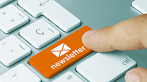 Ein Finger tippt auf die Taste "Newsletter" auf der Tastatur.