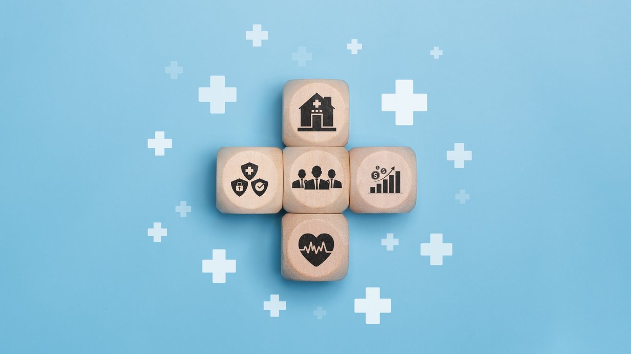 Bild zeigt vier Holzwürfel die zu einem Kreuz gelegt wurden mit verschiedenen Gesundheitssymbolen