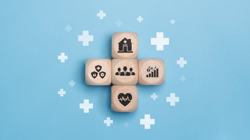 Bild zeigt vier Holzwürfel die zu einem Kreuz gelegt wurden mit verschiedenen Gesundheitssymbolen