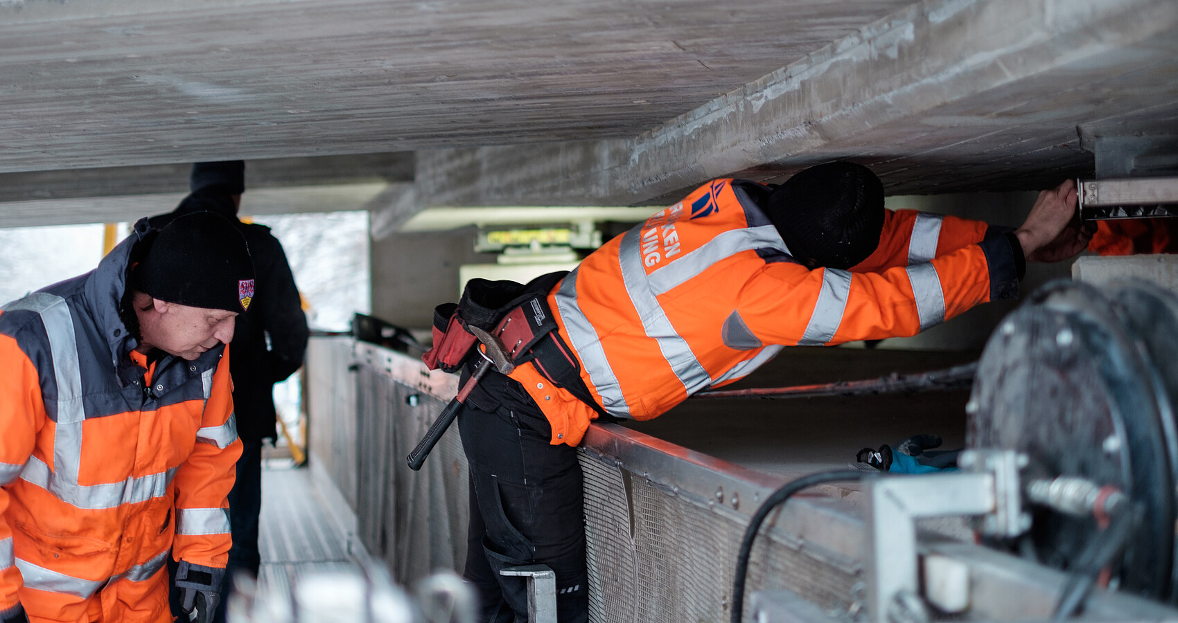 Zwei Arbeiter prüfen eine Brücke von unten