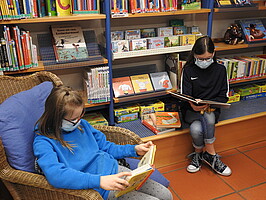 2 Mädchen mit Gesichtsmasken lesen in der Gemeindebücherei Starzach