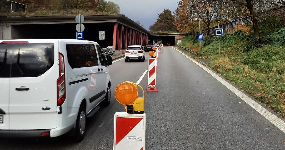 Das Foto zeigt den Wernerhoftunnel in Ravensburg. Die Straße ist mit mehreren Leitbaken auf eine Spur abgegrenzt. Mehrere Autos fahren auf der einen Spur in den Tunnel