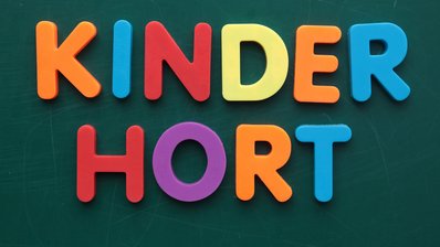 Kinderhort steht in bunten Holzbuchstaben, die an einer Tafel hängen