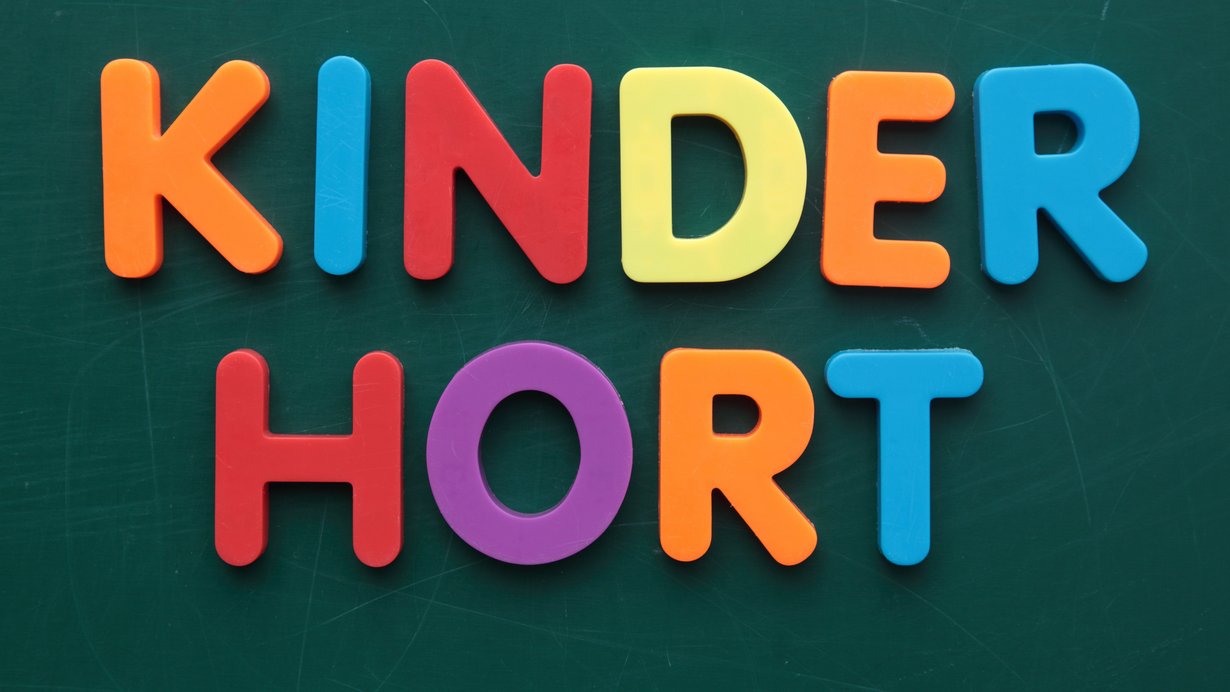 Kinderhort steht in bunten Holzbuchstaben, die an einer Tafel hängen