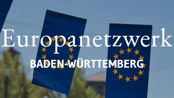 Das Bild zeigt zwei kleine EU-Flaggen (gelber Sternenkreis auf dunkelblauem Hintergrund). Im Hintergrund befinden sich leicht unscharf Bäume vor blauem Himmel. Auf dem Bild steht in weißer Schrift „Europanetzwerk“, darunter „Baden-Württemberg“.