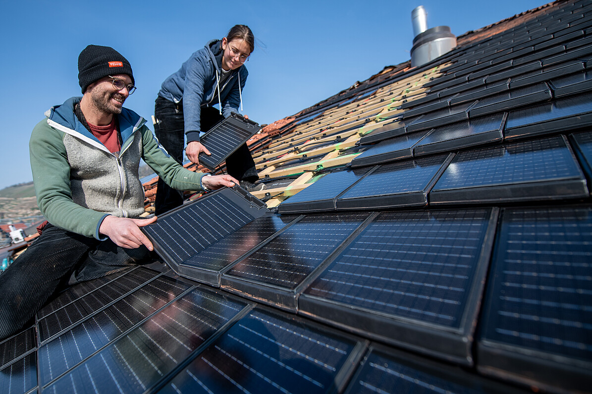 Zwei Männer montieren eine Photovoltaik-Anlage auf ein Dach