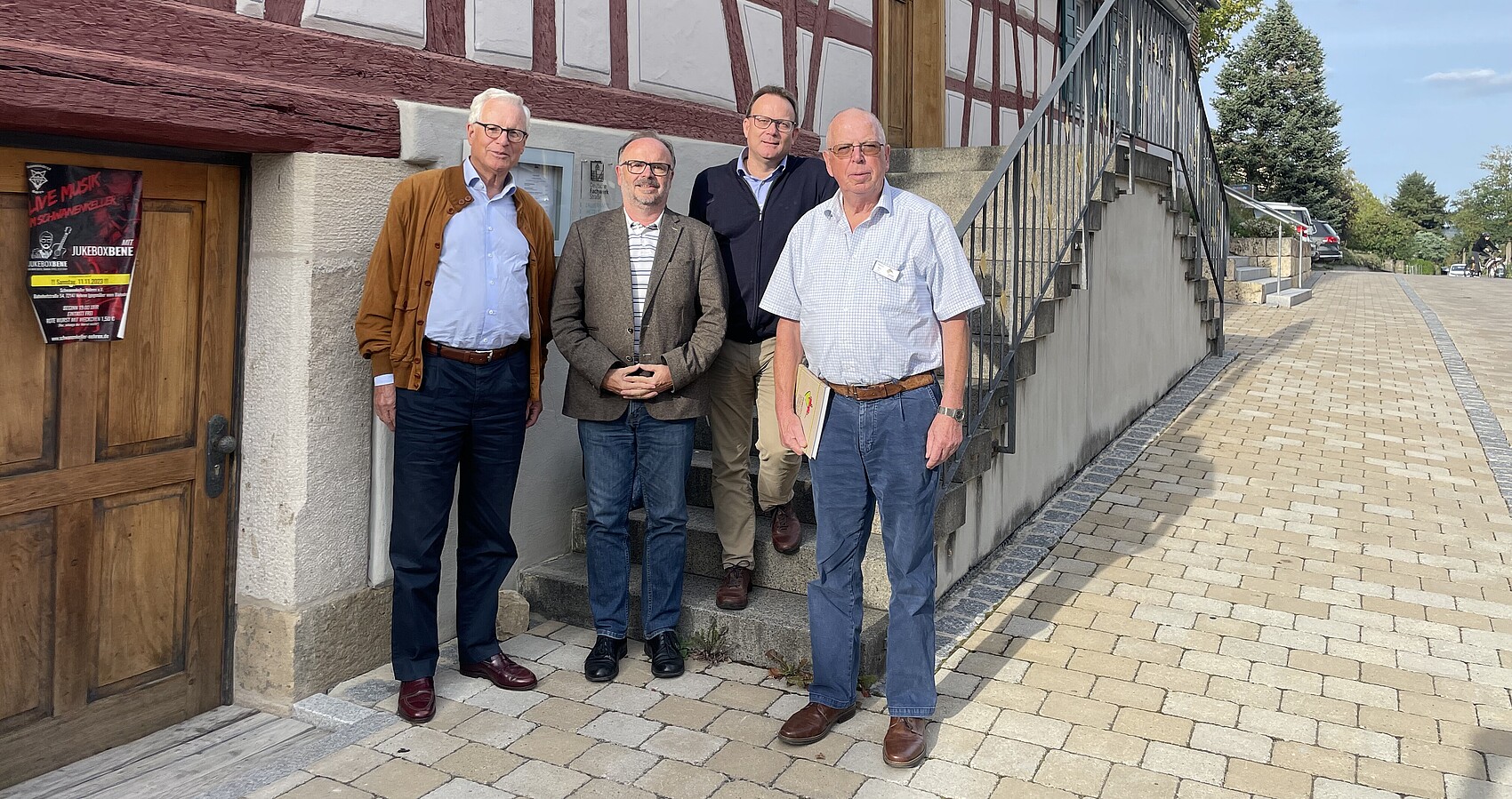 Das Foto zeigt die Jury des Wettbewerbs „Vorbildliches Dorfgasthaus“: Dr. Albrecht Rittmann, Karlheinz Geppert, Dr. Oliver Knörr, Harald Neu stehend vor einem Fachwerkgebäude