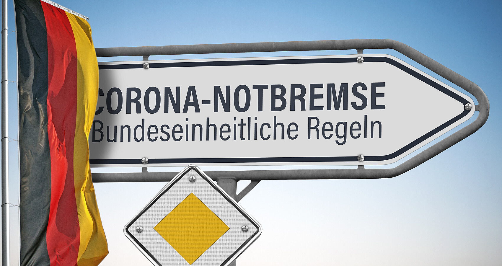 Schild mit Beschriftung CORONA-NOTBREMSE, Bundeseinheitliche Regeln; darunter ein Vorfahrtschild, links daneben die deutsche Nationalflagge