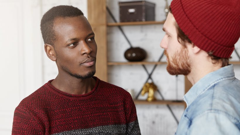 Bild zeigt Mann mit dunkler Hautfarbe, der einem Mann mit weißer Hautfarbe zuhört