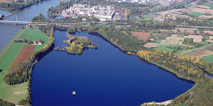 Luftaufnahme vom Knielinger See und Federbach am Rhein mit angrenzenden Äckern, Wiesen und Wäldern sowie Industrieanlagen und Versorgungseinrichtungen