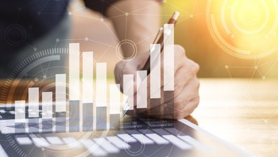 Symbolbild Wirtschaft; Mehrere Bilder sind übereinandergelagert. Man sieht einen Mann, der auf einem Computer arbeitet vor orangefarbenem Hintergrund, darüber sind Symbole für Wachstum und Wirtschaft gelegt. 