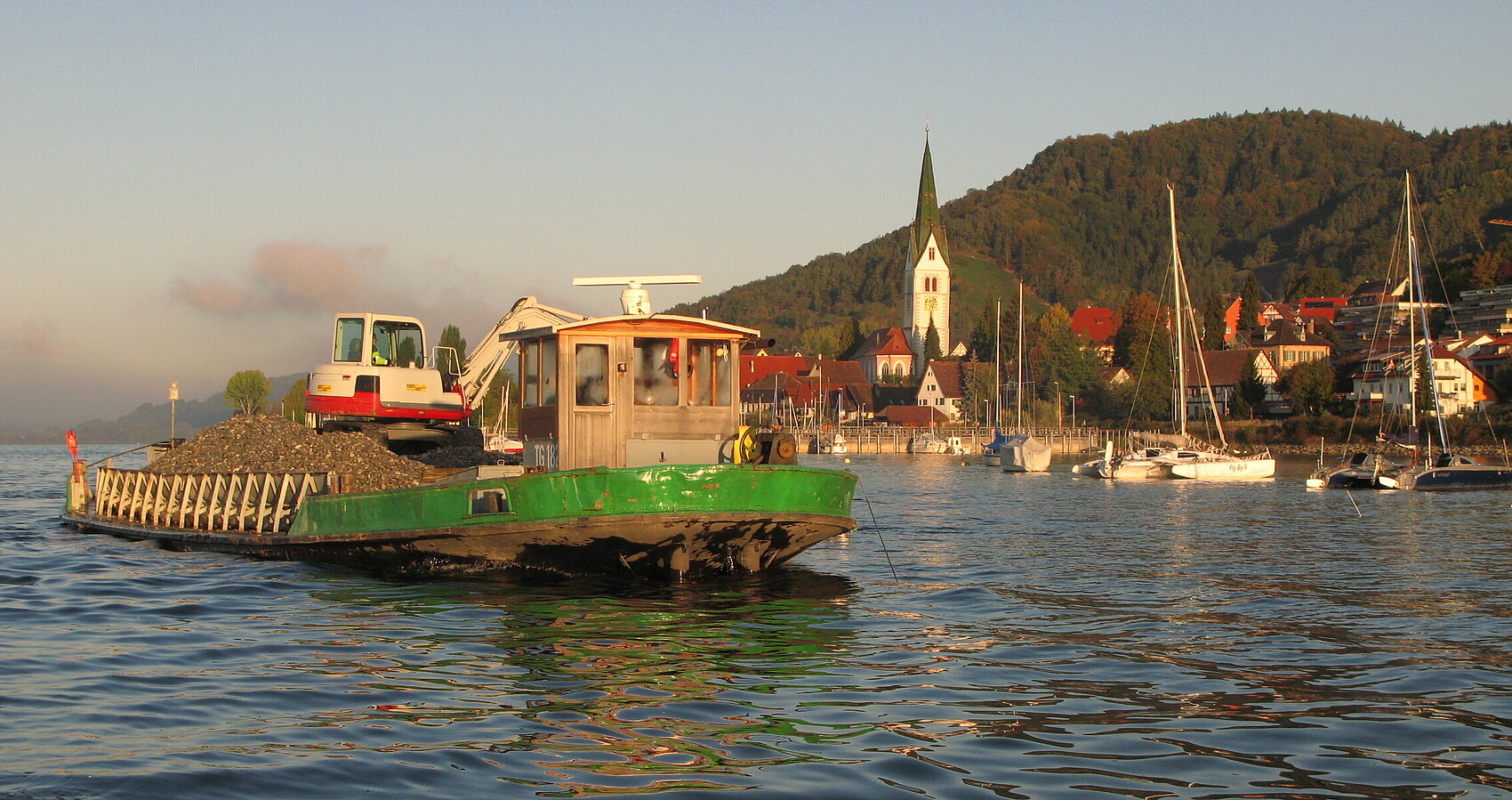 Bild zeigt ein Schiff auf dem See, im Hintergrund eine Stadt