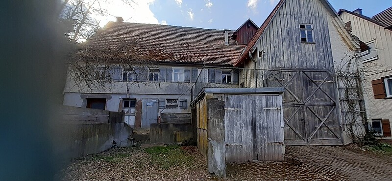 Das Bild zeigt die Rückseite eines alten Bauernhauses mit Scheune und Stall. 