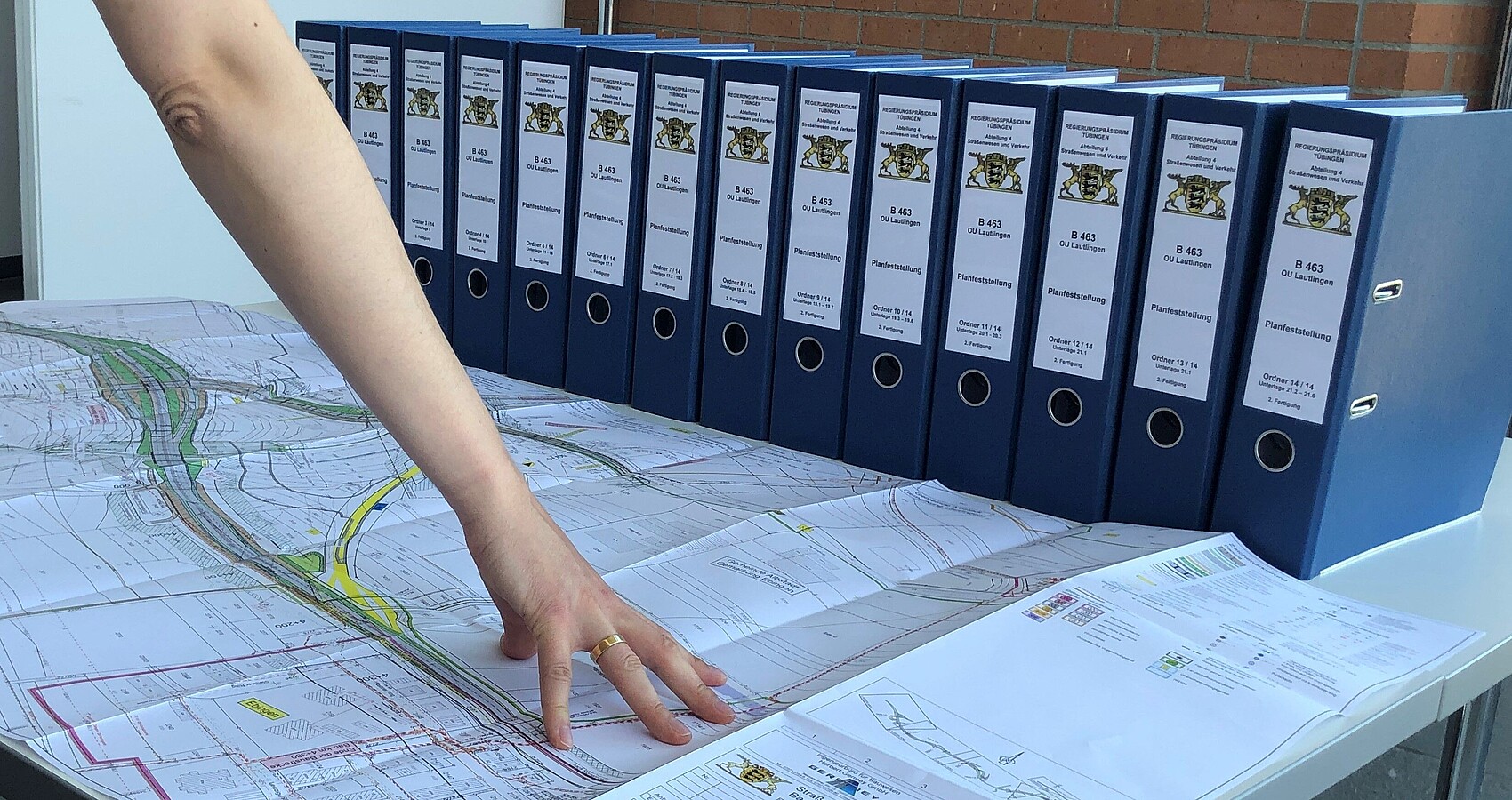 14 blaue Ordner und ein ausgebreiteter Plan zum Planfeststellungsverfahren für den Neubau der B 463 als Ortsumfahrung von Albstadt-Lautlingen auf einem Tisch