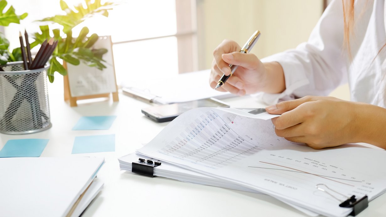 Frau sitzt a schreibtisch und prüft Unterlagen