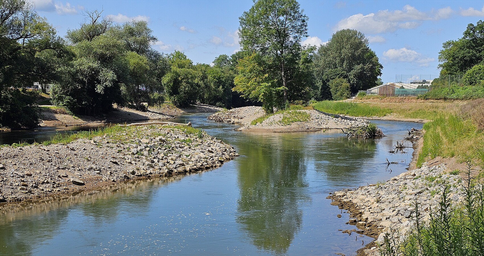 Foto nach der Revitalisierung des Flussparks Neckaraue; Man sieht den revitalisierten Neckar; links und rechts Kies und Sträucher