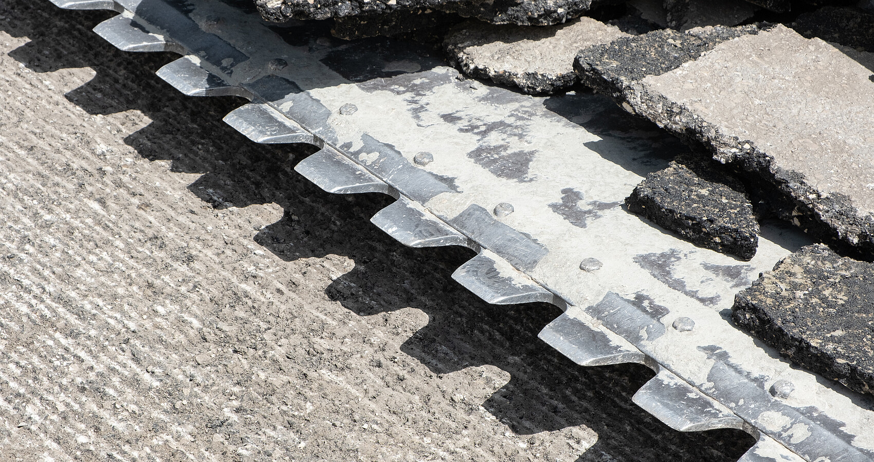 Baggerschaufel mit Stücken gebrochenen Asphalts entfernt Straßenbelag