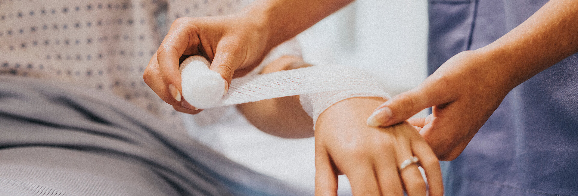 Eine Krankenschwester legt einer Frau einen Verband am Arm an