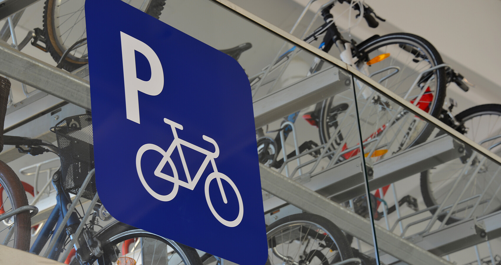 Fahrradparkplatz mit blauem Parkplatzschild darauf ein weißes "P" und ein weißes Fahrrad