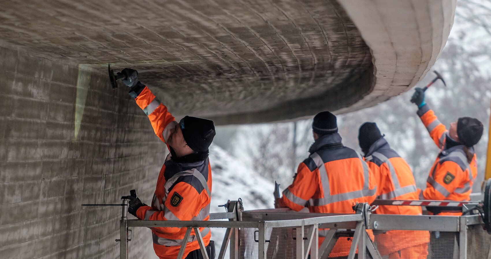 Vier Arbeiter prüfen eine Brücke