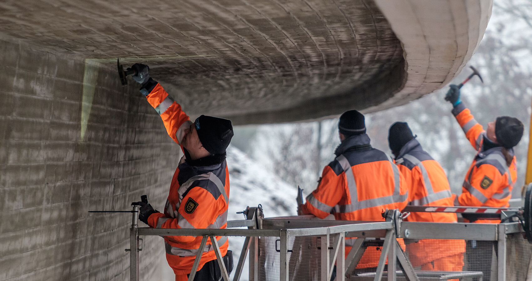 Vier Arbeiter prüfen eine Brücke