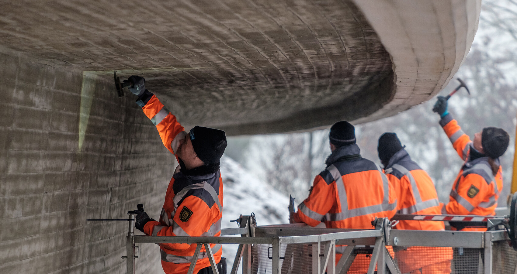 Vier Arbeiter prüfen eine Brücke