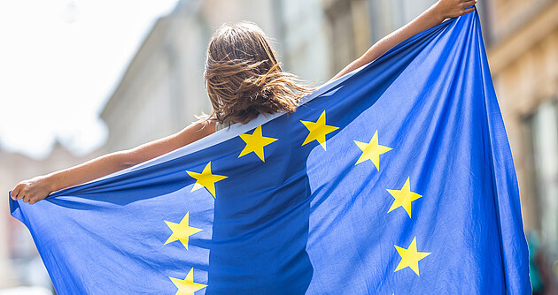 Eine Frau hält eine Europaflagge hinter ihrem Rücken