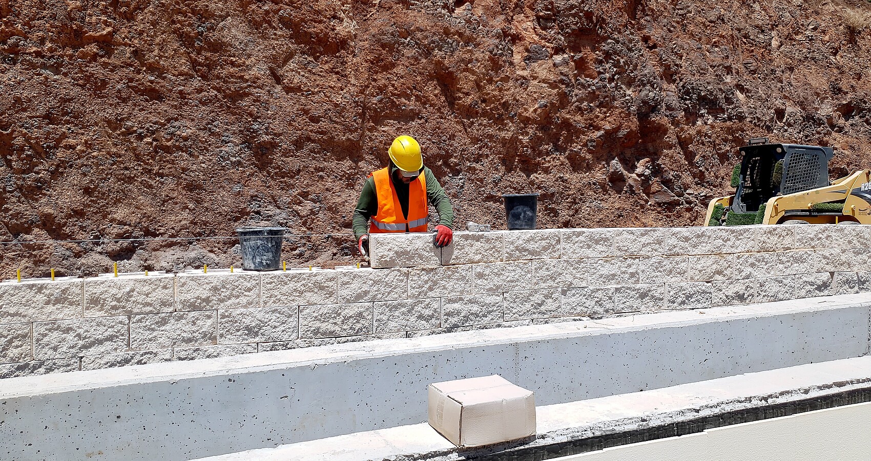 Bauarbeiter arbeitet an einer Stützmauer an einer Straße