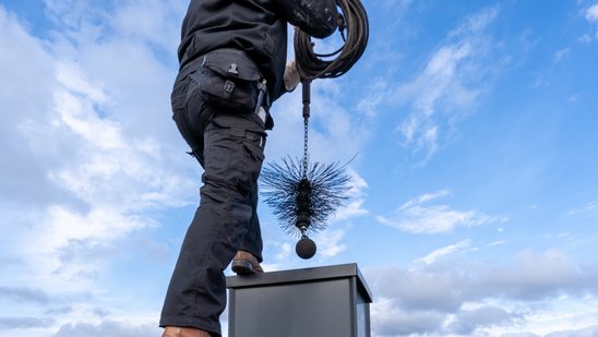 Bild zeigt einen Schornsteinfeger auf einem Dach
