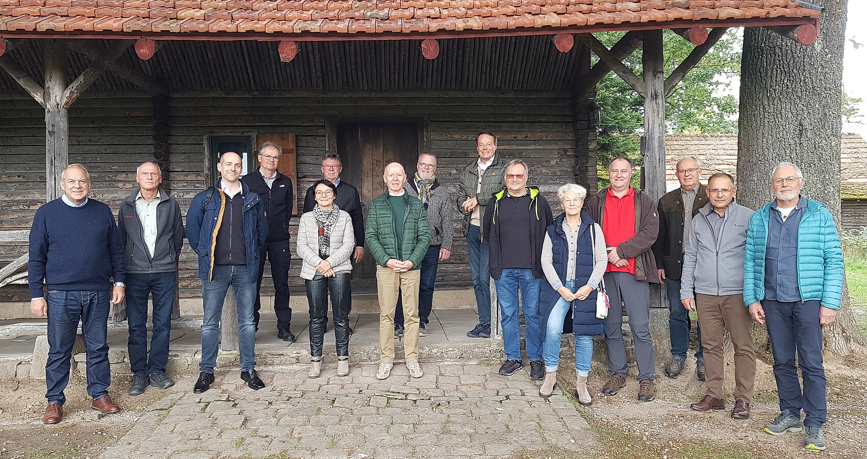Im Bild stehen die Naturschutzbeaufragten gemeinsam mit dem Rgeirungspräsidenten und Vertreterinnen und Vertretern des Regierungspräsidums Tübingen vor einer Hütte im Wald.