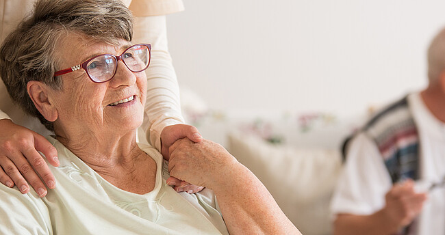 Senioren hlt lächelnd die Hand der Pflegerin