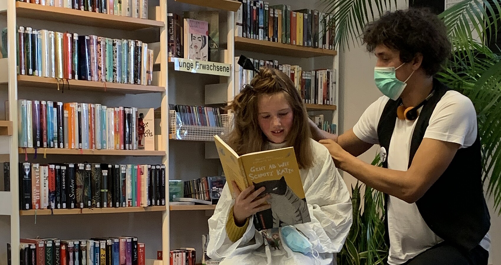 Ein Friseur schneidet einem Mädchen in einer Stadtbibliothek die Haare