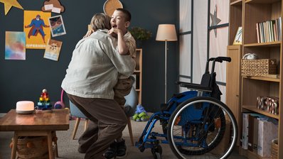 Eine Frau hilft einem behinderten Kind in den Rollstuhl