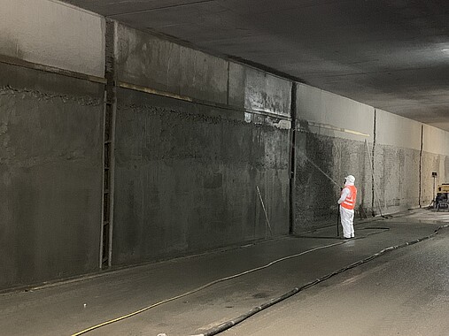 Ein Arbeiter sprüht Beton auf die Innenwand eines Tunnels. 