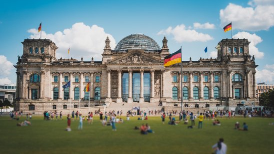 Viele Menschen an einem sonnnigen Tag auf der Wiese vor dem Reichstagsgebäude in Berlin