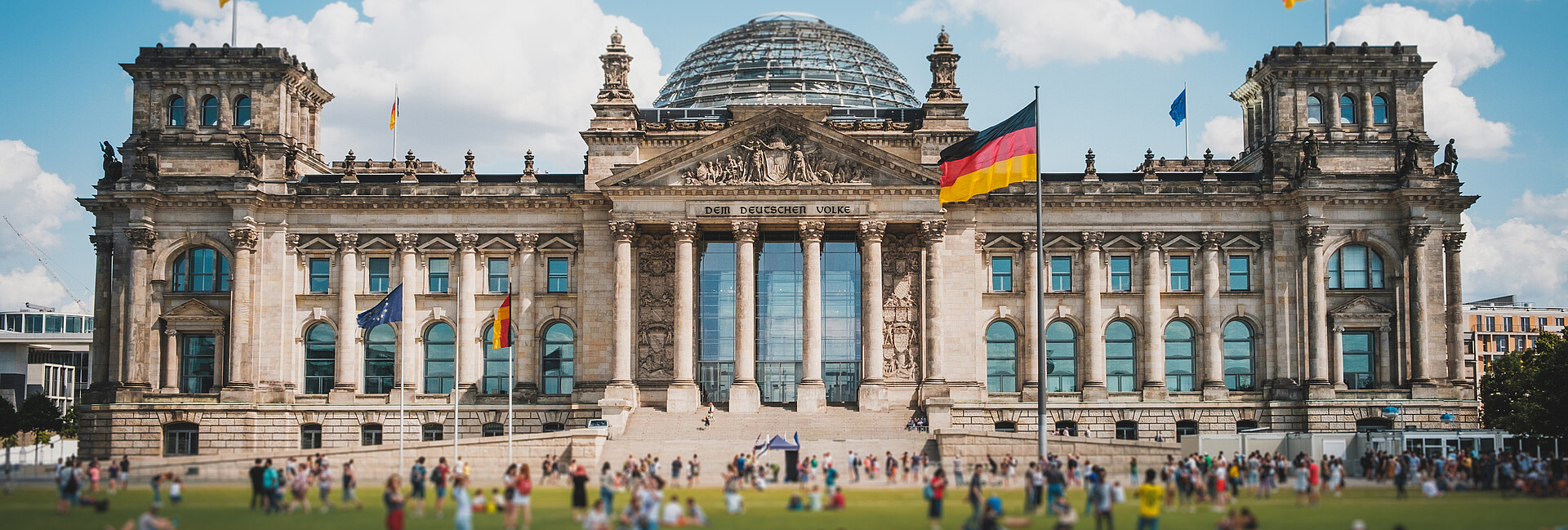 Viele Menschen an einem sonnnigen Tag auf der Wiese vor dem Reichstagsgebäude in Berlin