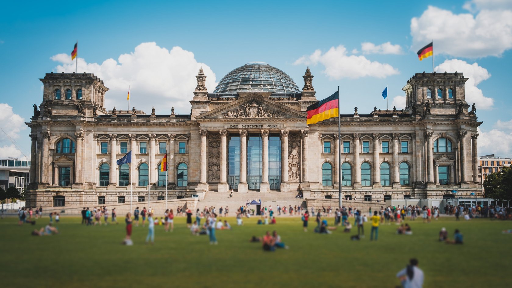 Viele Menschen an einem sonnnigen Tag auf der Wiese vor dem Reichstagsgebäude in Berlin