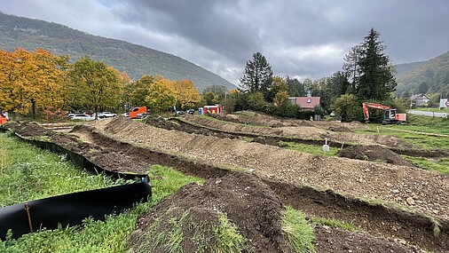 Eine Wiese, auf der mehrere lange Gräben verlaufen. Die Erde ist jeweils neben den Gräben zu kleinen Wällen aufgeschüttet. 