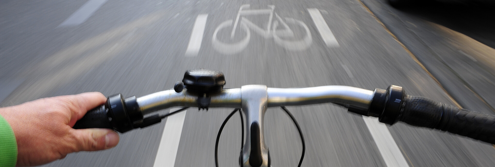 Blick über den Lenker:Fahrrad in schneller Fahrt auf einem Fahrradweg