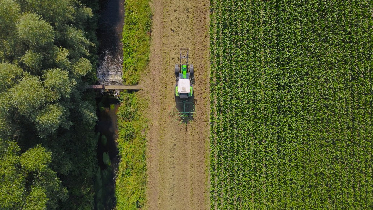 Traktor fährt entlang eines Gewässerrandstreifens