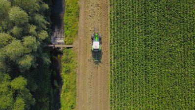 Traktor fährt entlang eines Gewässerrandstreifens