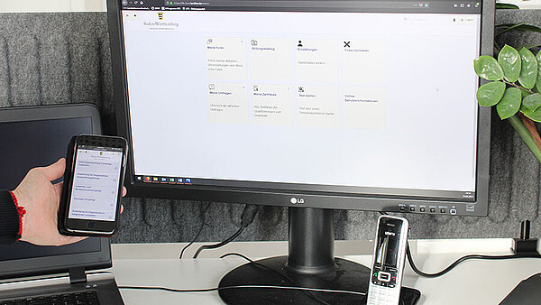 Computerbildschirm der die Anmeldemaske des Bildungsportal zeigt und daneben ein Handy mit der gleichen Anmeldemaske